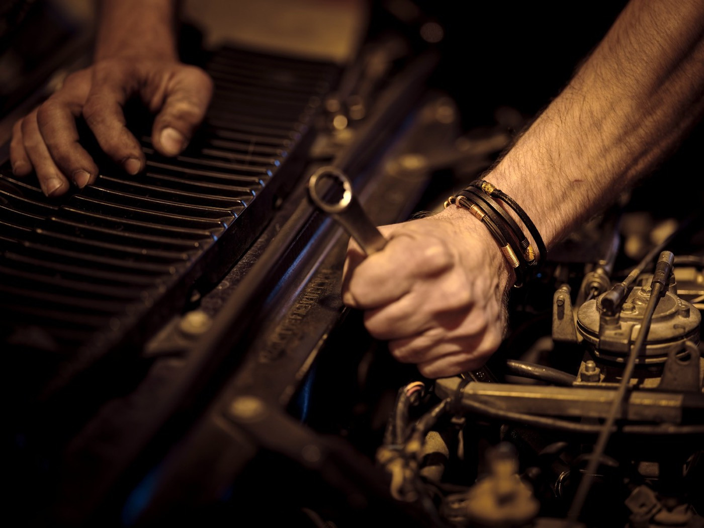 A technician’s hands working on an engine with a wrench.